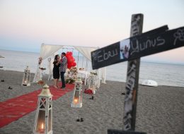 Ürkmez’de Plajda Evlenme Teklifi Organizasyonu 12 İzmir Organizasyon Ürkmez’de Plajda Evlenme Teklifi Organizasyonu; yazı ayrı, kışın ayrı güzelliği vardır. Kentsel gelişmeye karşı dirençli olması en çok sevilen özelliklerden biridir. Mandalinasının ve hatta balığının lezzetini hiç bir yerde bulamadığınız şirin belde. Gümüldür ile Seferihisar arasına sıkışmış az kişinin bildiği sığınılası sahil kasabasıdır Ürkmezdir. Yunus Bey kız arkadaşı Ebru hanım ile olan beraberliklerini, bir ömür boyu yan yana geçirmek istediğine kanaat getirmişti. Ebru hanımla evlilik yolunda ilerlemek istediğine karar veren Yunus bey, peri masalı gibi akıllardan silinmeyecek bir evlenme teklifi organizasyonu yapmak istiyordu. Böyle bir organizasyon için kolları sıvamış ve internetten araştırarak İzmir Organizasyon şirketini sadece birkaç gün önce bulmuş yani bizimle çalışmaya karar vermişti. Yunus bey ofisimize gelip bizimle görüşme fırsatı yakalayamamış, görüşmelerimizi telefonda gerçekleştirmiştik. Kız arkadaşı ile ikisinin de tam bir deniz aşığı olduğunu söyledi ve Ürkmez lokasyonunun hem kendilerine yakın hem de en favori tatil beldesi olduğunu dile getirdi. Ayrıca öyle bir zamanlama yaptı ki yakın arkadaşlarının düğünü olduğu güne denk getirdi evlenme teklifi organizasyonunu. Dolayısıyla biz de o tarihte, deniz kenarında bir evlenme teklifi organizasyonu yapabileceğimiz bahsettik kendisine. Ürkmez Plajda Evlenme Teklifi Organizasyonu