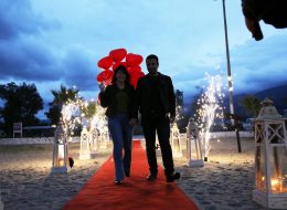 Kuşadası’nda Kumsal Boyu Evlenme Teklifi Organizasyonu İzmir Organizasyon Kuşadası Evlenme Teklifi Organizasyonu Nihal Fatih 2 İzmir Organizasyon Kuşadası'nda evlenme teklifi organizasyonu ile evlilik yolunda ilk adımı atmak isteyen çiftimize özel bir evlilik teklifi organizasyonu hazırladık. Fatih Bey kız arkadaşı Nihal hanım ile olan beraberliklerini, bir ömür boyu yan yana geçirmek istediğine kanaat getirmişti. Nihal hanımla evlilik yolunda ilerlemek istediğine karar veren Fatih bey, peri masalı gibi akıllardan silinmeyecek bir evlenme teklifi organizasyonu yapmak istiyordu. Böyle bir organizasyon için kolları sıvamış ve internetten araştırarak İzmir Organizasyon şirketini bulmuş yani bizimle çalışmaya karar vermişti. Fatih bey ofisimize gelip bizimle görüşürken; kız arkadaşı ile ikisinin de tam bir deniz aşığı olduğunu söyledi ve Kuşadası lokasyonunun hem kendilerine yakın hem de en favori tatil beldesi olduğunu dile getirdi. Dolayısıyla biz de deniz kenarında ve Kuşadası’nda bir evlenme teklifi organizasyonu yapabileceğimiz bahsettik kendisine. Kumsalda romantik bir evlenme teklifi organizasyonu genç çiftimizi için en güzel seçenek olduğuna kanaat getirdik Fatih bey ile. Görüşmemizin ilerleyen dakikalarında Fatih bey ile organizasyonu gerçekleştireceğimiz günü, saati ve çiftimizin en sevdiği şarkıyı kararlaştırdık. Hava şartları da çok önemliydi. Kış aylarında yağmuru ve rüzgarı baz alarak takvimleri inceledik. Hava inceden lodosun hafif kımıltısını gösteriyordu ve durum bu güzel evlenme teklifi organizasyonuna oldukça uygundu. Fatih bey için geriye sadece heyecanla evlilik teklifi organizasyonu yapacağı günü beklemek, ekip arkadaşlarımız için ise her zaman ki gibi kusursuz bir evlenme teklifi organizasyonu hazırlamak kalmıştı. Kuşadası’nda Kumsal Boyu Evlenme Teklifi Organizasyonu İzmir Organizasyon Kuşadası Evlenme Teklifi Organizasyonu Nihal Fatih 2 İzmir Organizasyon