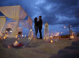 Kuşadası’nda Kumsal Boyu Evlenme Teklifi Organizasyonu İzmir Organizasyon Kuşadası Evlenme Teklifi Organizasyonu Nihal Fatih 7 İzmir Organizasyon Kuşadası'nda evlenme teklifi organizasyonu ile evlilik yolunda ilk adımı atmak isteyen çiftimize özel bir evlilik teklifi organizasyonu hazırladık. Fatih Bey kız arkadaşı Nihal hanım ile olan beraberliklerini, bir ömür boyu yan yana geçirmek istediğine kanaat getirmişti. Nihal hanımla evlilik yolunda ilerlemek istediğine karar veren Fatih bey, peri masalı gibi akıllardan silinmeyecek bir evlenme teklifi organizasyonu yapmak istiyordu. Böyle bir organizasyon için kolları sıvamış ve internetten araştırarak İzmir Organizasyon şirketini bulmuş yani bizimle çalışmaya karar vermişti. Fatih bey ofisimize gelip bizimle görüşürken; kız arkadaşı ile ikisinin de tam bir deniz aşığı olduğunu söyledi ve Kuşadası lokasyonunun hem kendilerine yakın hem de en favori tatil beldesi olduğunu dile getirdi. Dolayısıyla biz de deniz kenarında ve Kuşadası’nda bir evlenme teklifi organizasyonu yapabileceğimiz bahsettik kendisine. Kumsalda romantik bir evlenme teklifi organizasyonu genç çiftimizi için en güzel seçenek olduğuna kanaat getirdik Fatih bey ile. Görüşmemizin ilerleyen dakikalarında Fatih bey ile organizasyonu gerçekleştireceğimiz günü, saati ve çiftimizin en sevdiği şarkıyı kararlaştırdık. Hava şartları da çok önemliydi. Kış aylarında yağmuru ve rüzgarı baz alarak takvimleri inceledik. Hava inceden lodosun hafif kımıltısını gösteriyordu ve durum bu güzel evlenme teklifi organizasyonuna oldukça uygundu. Fatih bey için geriye sadece heyecanla evlilik teklifi organizasyonu yapacağı günü beklemek, ekip arkadaşlarımız için ise her zaman ki gibi kusursuz bir evlenme teklifi organizasyonu hazırlamak kalmıştı. Deniz Kenarında Evlenme Teklifi Organizasyonu Romantik Dakikalar